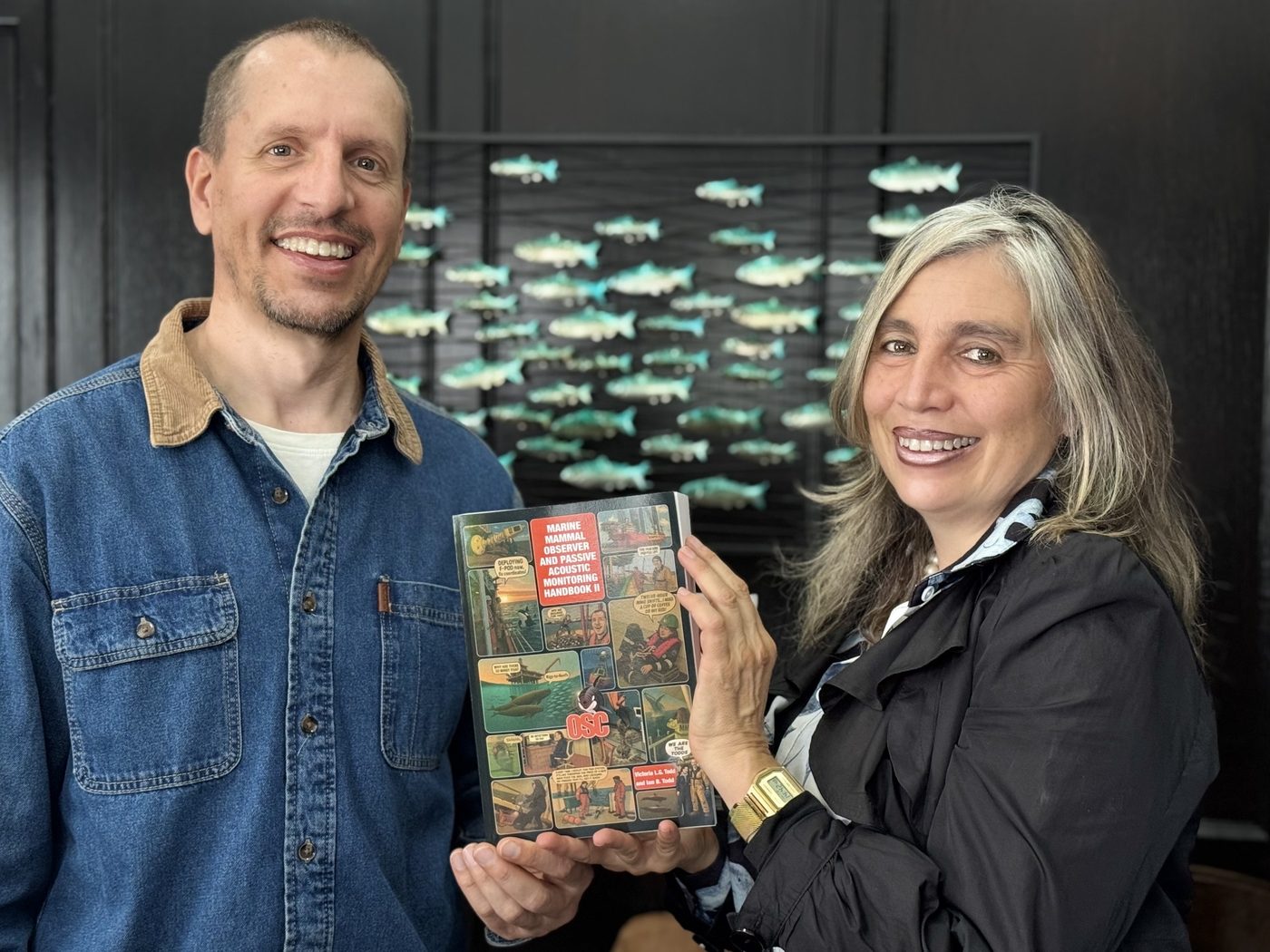 Ian Todd and Dr. Victoria Todd holding a copy of the Marine Mammal Observer and Passive Acoustic Monitoring Handbook II